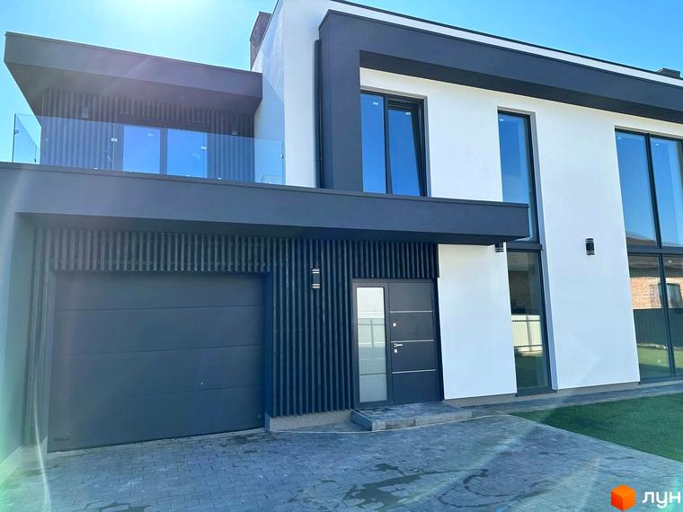 Котеджне містечко КМ PARK by berezivka. Фасад двоповерхового будинку з великими вікнами та гаражем, перед будинком вимощена доріжка.