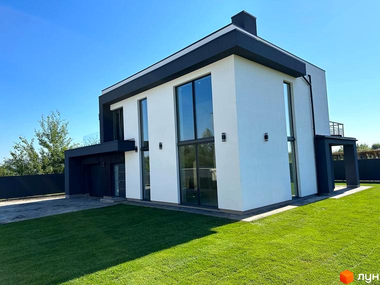 Екстер'єр будинку в КМ PARK by berezivka з великими вікнами та білою стіною на тлі блакитного неба. Доглянутий зелений газон перед будинком.