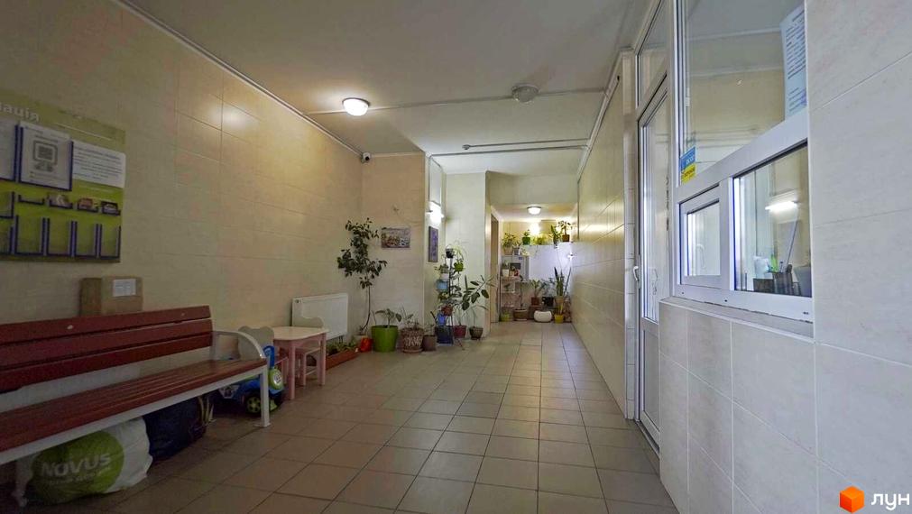 Вхідна група житлового комплексу Саперно-Слобідська, 24 з лавкою та дитячим столиком. Коридор з плиткою на стінах та підлозі, освітленням та рослинами.