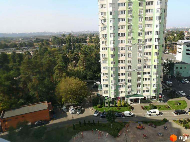 Багатоповерховий житловий будинок Житлового комплексу Паркові озера зі світло-зеленим та білим фасадом. Прибудинкова територія має парковку, дитячий майданчик та зелені насадження.