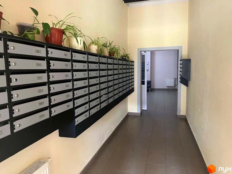 Внутрішній вигляд житлового комплексу Воскресенський з поштовими скриньками та рослинами на стіні.