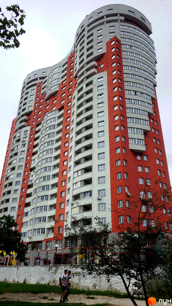 Житловий комплекс Воскресенський: висотна будівля з хвилястим фасадом червоно-сірого кольору. На передньому плані зелена зона з деревами та пішоходами.