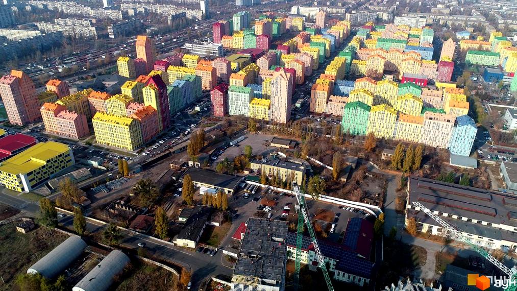 Житловий комплекс Комфорт Таун з кольоровими будинками та прибудинковою територією. Вид на парковку та навколишні будівлі.