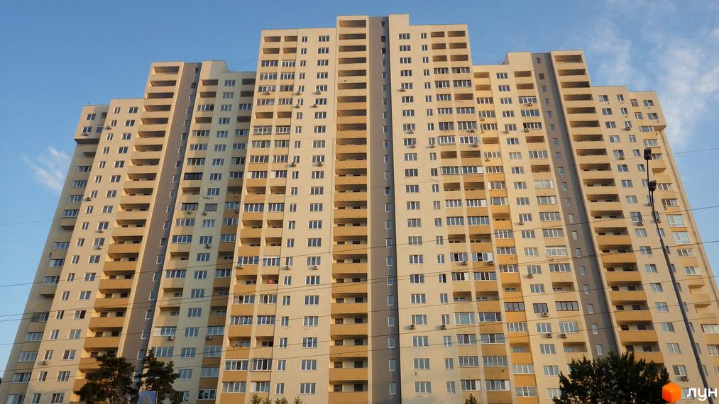 Житловий комплекс Перовський з висотними будинками та балконами. Прибудинкова територія з зеленими насадженнями та доріжками.