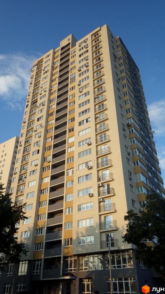 Житловий комплекс Перовський з висотним будинком, обладнаним балконами. Прибудинкова територія озеленена деревами та кущами.