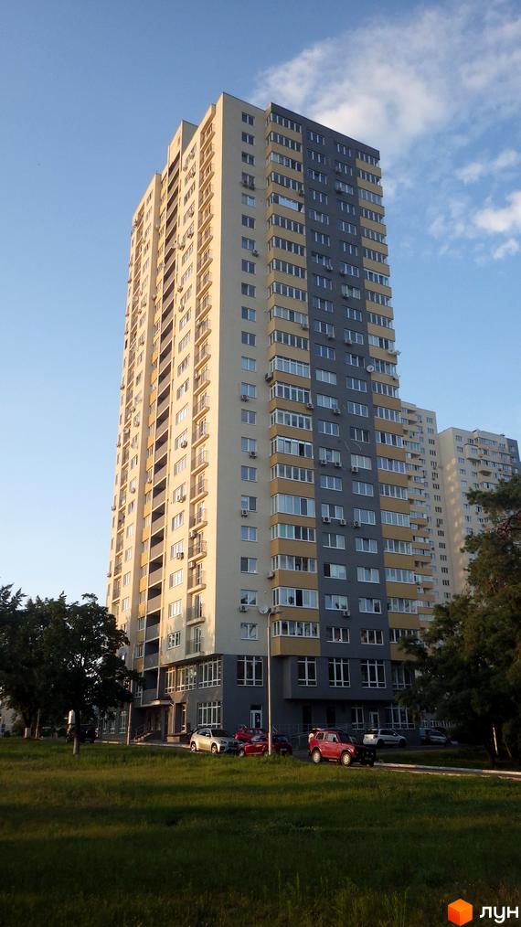 Житловий комплекс Перовський з сучасним фасадом та прибудинковою територією, озелененням і паркувальними місцями.