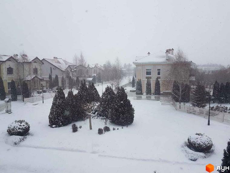 Зимовий пейзаж Котеджного містечка Аріадна. Будинки з черепичними дахами та засніжені дерева на прибудинковій території.