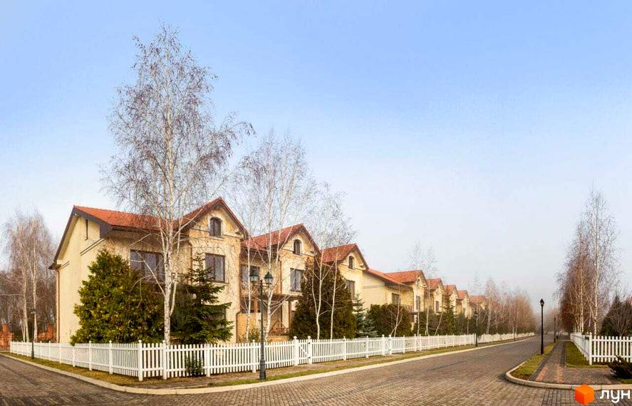 Зображення будинків у Котеджному містечку Аріадна з червоними дахами та білим парканом. Навколо будівель ростуть дерева та кущі.