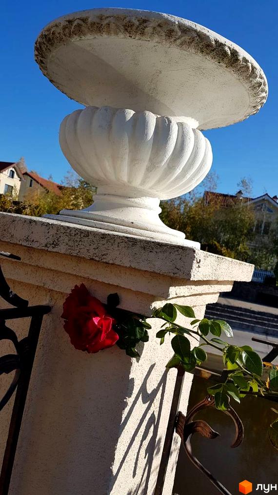 Фото вази з квітами на території Котеджного містечка Аріадна. Вигляд фасаду будинку та ландшафтний дизайн.