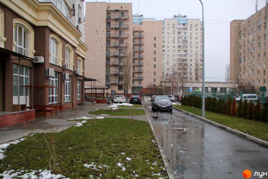 Зовнішній вигляд будинку в Житловому комплексі Оболонь Тауер. На передньому плані прибудинкова територія з газоном та тротуаром.