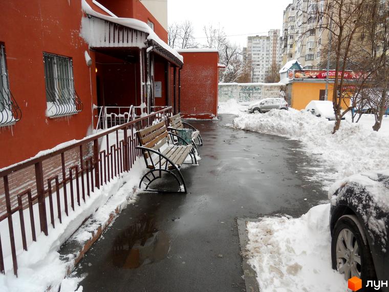 Зимовий пейзаж біля Житлового комплексу Мінський. Вигляд на будівлю та засніжену прибудинкову територію з лавками.