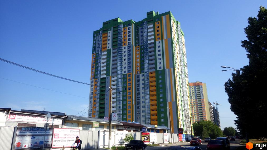 Новобудова на вул. Петра Калнишевського (Майорова), 6. Багатоповерховий житловий комплекс з яскравим фасадом у зелених, жовтих та сірих кольорах. Поруч розташовані інші будівлі та дерева.