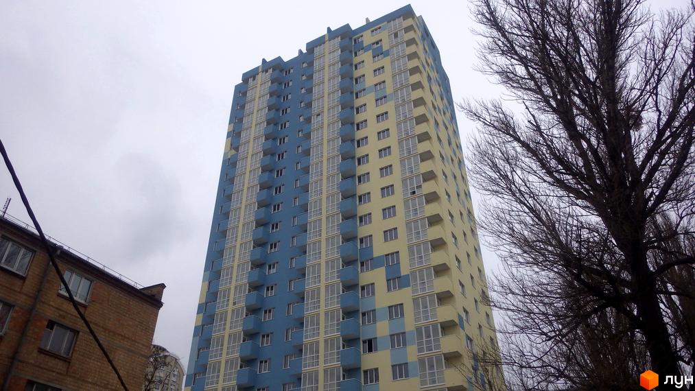 Фасад новобудови ЖК Вишиванка у блакитно-жовтих тонах. Багатоповерховий будинок з балконами та великими вікнами.