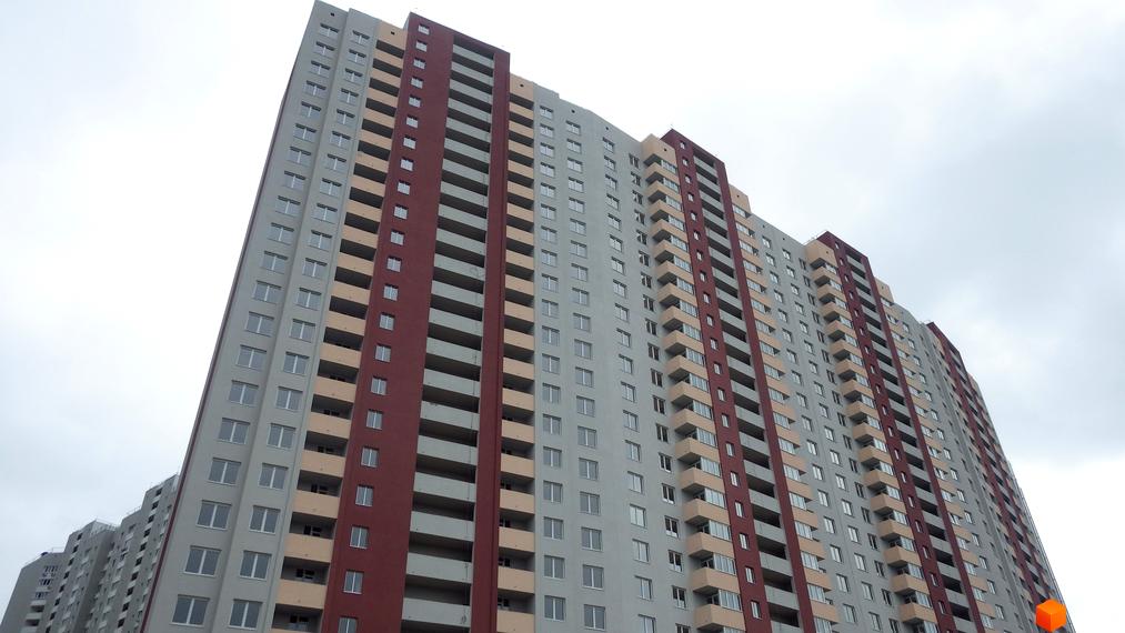 Багатоповерховий будинок Житлового комплексу Navigator з сірим, бордовим та бежевим фасадом. Видно численні вікна та балкони.