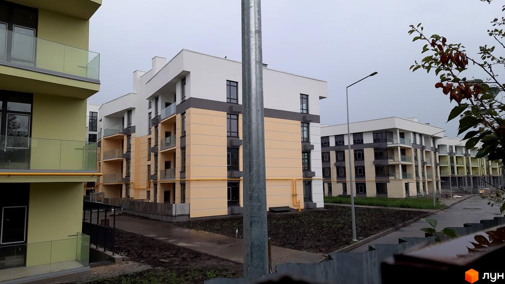 Комплекс Італійський квартал. Будинки з жовто-білими фасадами та скляними балконами. Прибудинкова територія з дорогою та зеленими насадженнями.