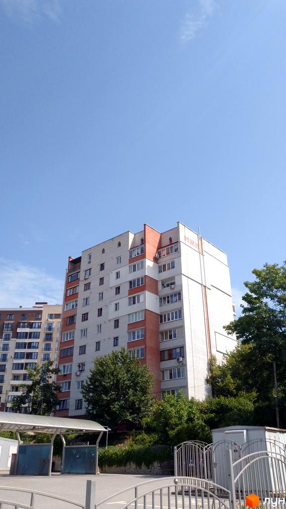 Зовнішній вигляд багатоквартирного будинку вул. 15 Квітня, 2д, з цегляним оздобленням та прибудинковою територією з навісом.