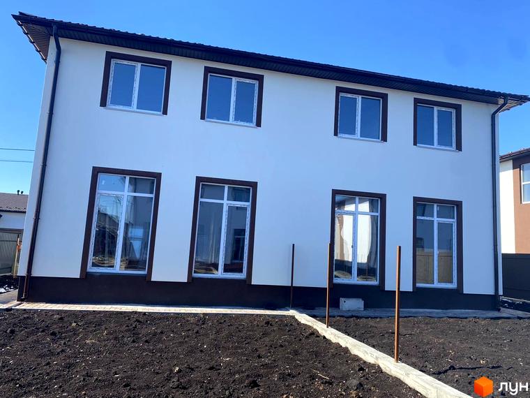 Двоповерховий будинок з білою стіною та коричневими віконними рамами житлового комплексу