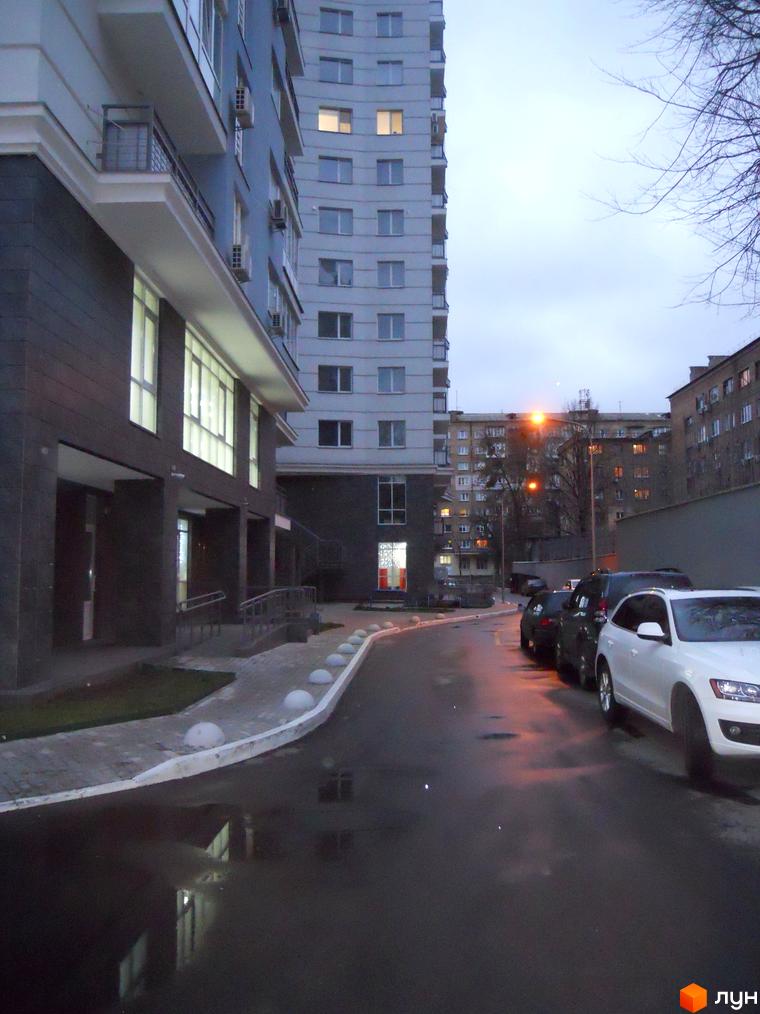 Житловий комплекс Срібна Вежа з сучасною архітектурою. Прибудинкова територія з асфальтованою дорогою та паркувальними місцями.