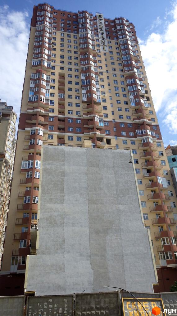 Житловий комплекс Елегант з фасадом, що складається з балконів та великих вікон. Прибудинкова територія з огорожею та будівельними роботами.
