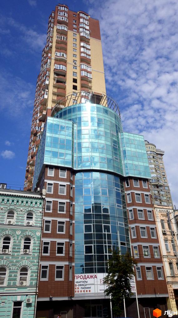 Житловий комплекс Елегант з сучасним фасадом, великими вікнами та прибудинковою територією. На фоні видно інші будівлі міста.