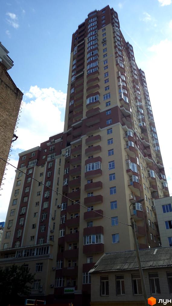 Житловий комплекс Елегант: висока багатоповерхова будівля бежевого та темно-коричневого кольорів з численними вікнами та балконами. Поруч розташовані інші споруди.