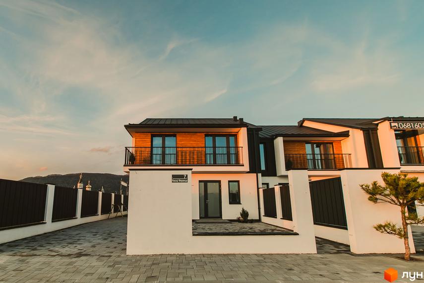 Таунхауси Modern House з білими фасадами та дерев'яними елементами, розташовані біля вимощеної бруківкою доріжки та паркану.