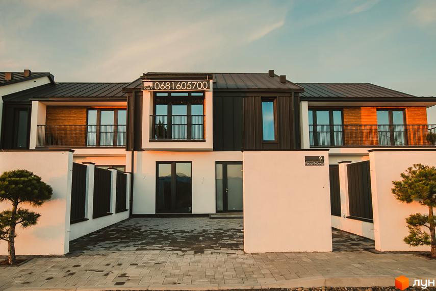 Таунхауси Modern House з чорними дахами та дерев'яними елементами фасаду. Прибудинкова територія з бруківкою та огорожею.