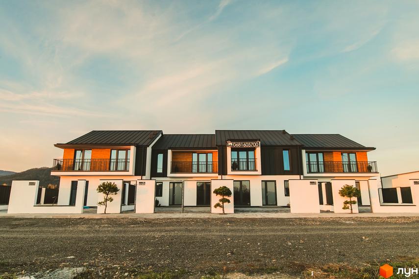 Таунхауси Modern House з чорним дахом та дерев'яними елементами фасаду. Перед будинками розташована прибудинкова територія з доріжками та декоративними деревами.