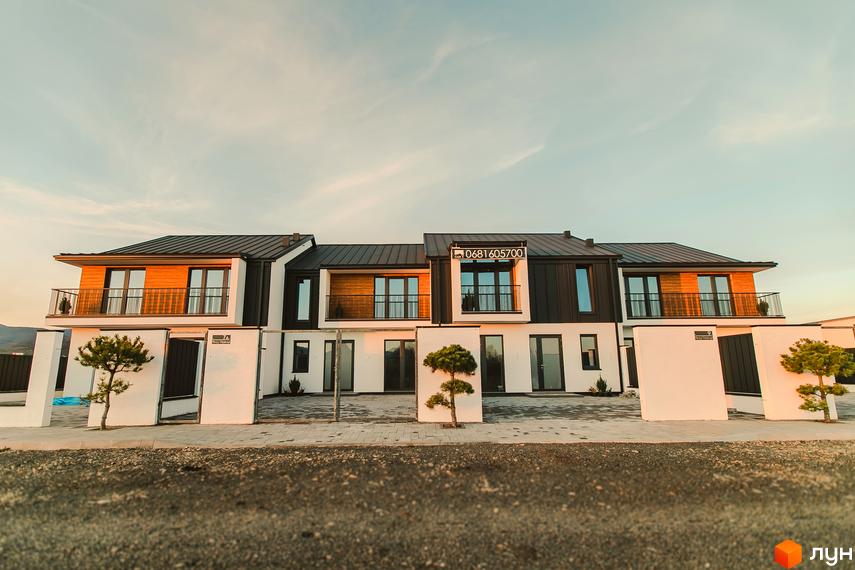 Таунхауси Modern House - фасади з дерев'яними вставками та великими вікнами, перед будинками доглянута територія з деревами та бруківкою.