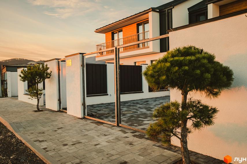 Таунхауси Modern House - це сучасні будинки з панорамними вікнами та балконами, розташовані на вимощеній плиткою території з доглянутими деревами.