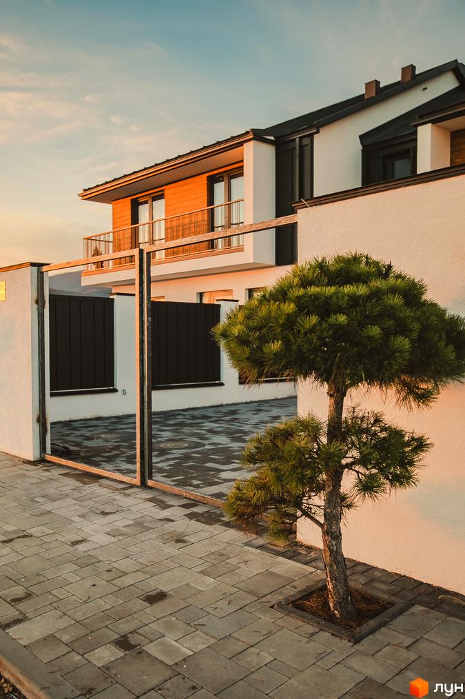 Таунхауси Modern House з дерев'яними елементами фасаду та доглянутою прибудинковою територією з акуратно підстриженою сосною.