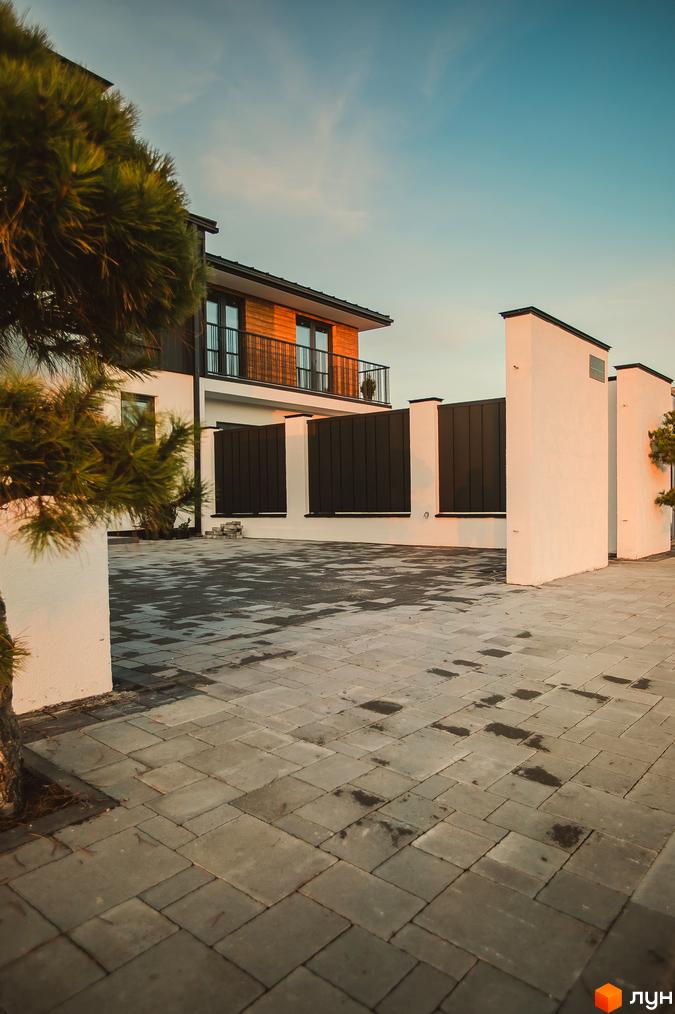 Таунхауси Modern House: двоповерховий будинок з дерев'яним фасадом та балконом, огороджена територія з бруківкою та парканом.