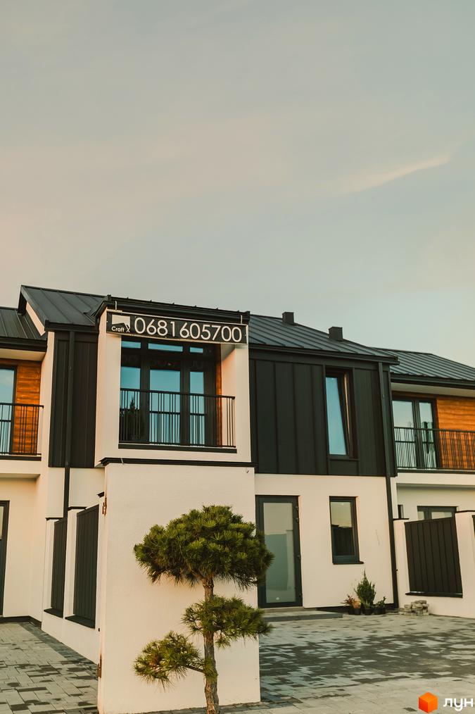 Таунхауси Modern House з біло-чорним фасадом та балконами, перед якими росте декоративне дерево.