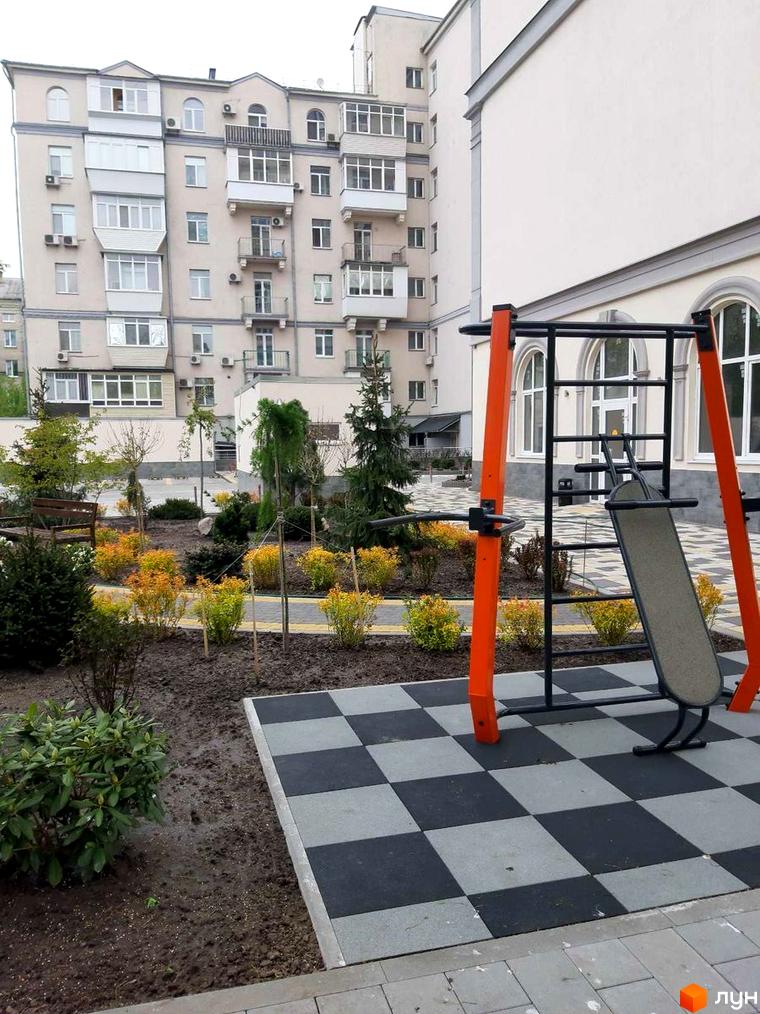 Житловий комплекс Дом на Строителей. Зовнішній вигляд будинку та прибудинкова територія зі спортивним майданчиком.