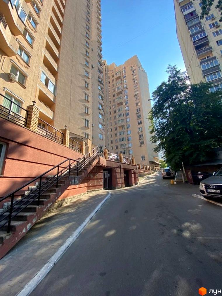 Зовнішній вигляд житлового комплексу на вул. Липківського, 18, 18в, з прибудинковою територією та автомобілями.