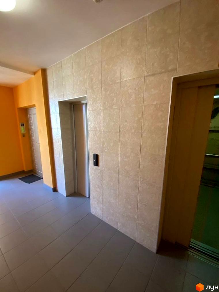 Внутрішній вигляд ліфтової зони житлового комплексу на вул. Липківського, 18, з плиткою на стінах та підлозі.