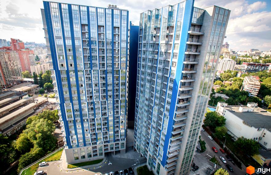 Житловий комплекс Central Park – це дві висотні будівлі з блакитними та сірими фасадами, що розташовані поруч. Навколо комплексу видно зелені насадження та міську забудову.
