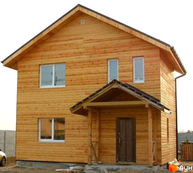 Двоповерховий дерев'яний будинок у Котеджному містечку Солнечная Поляна. Світло-коричневий фасад, білі вікна та темний дах.