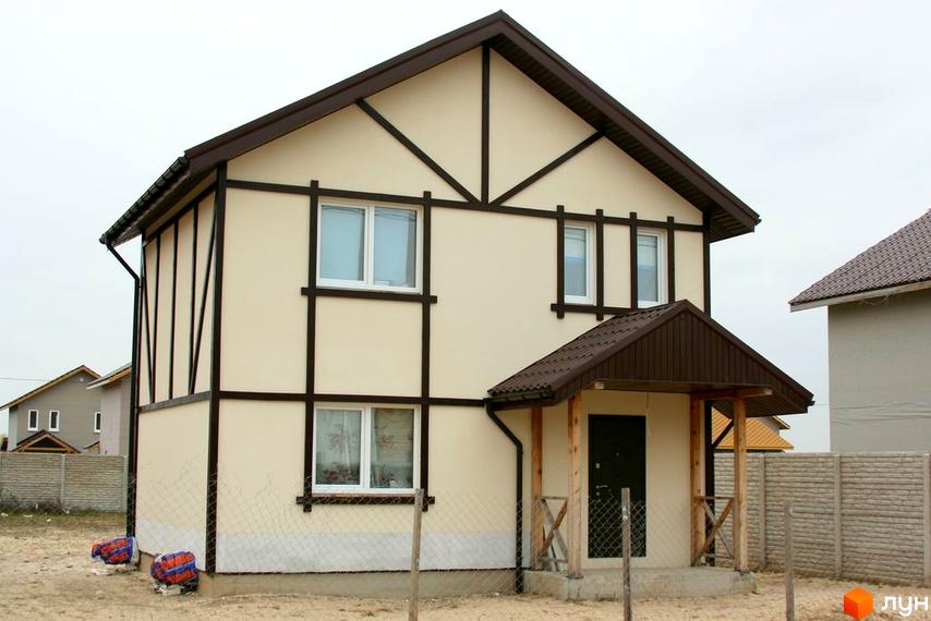 Зображення двоповерхового будинку в Котеджному містечку Солнечная Поляна. Світлий фасад та коричневий дах, охайна прибудинкова територія.