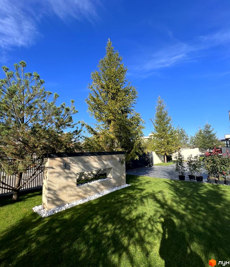 Зображення території Котеджного містечка Riviera City Park з ландшафтним дизайном. На передньому плані газон, дерева та декоративні елементи.