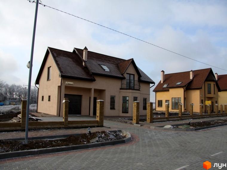 Зовнішній вигляд будинків у житловому комплексі КМ Європа, прибудинкова територія з доріжками та освітленням.