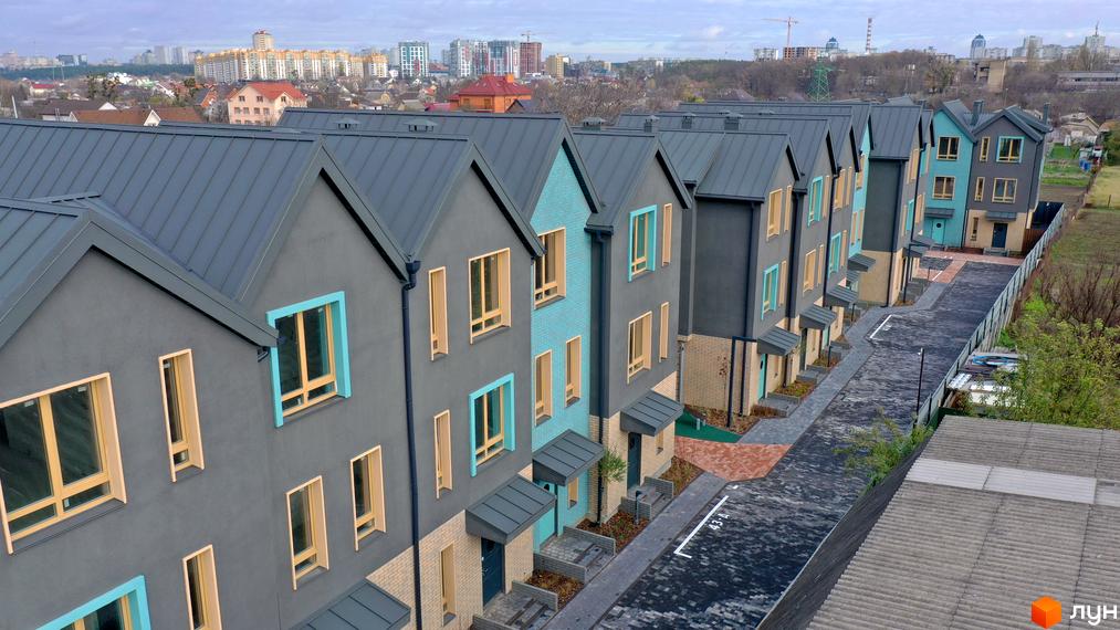 Таунхауси New Smart 13 з сірими фасадами та блакитними акцентами, розташовані вздовж бруківки.