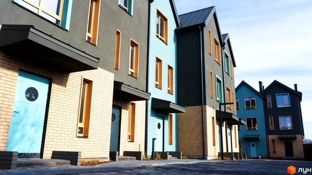 Фасад таунхаусів New Smart 13 з цегляними та штукатуреними елементами, блакитними та сірими кольорами, та бруківкою перед будинками.