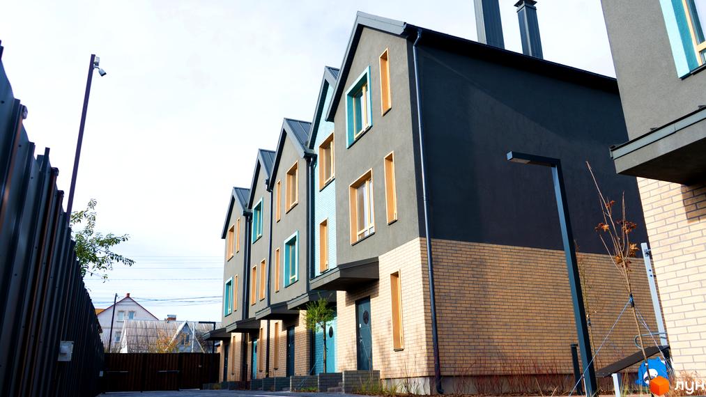 Таунхауси New Smart 13 – це сучасні будинки з цегляним оздобленням фасаду та яскравими вікнами. На території новобудови розташовані ліхтарі та зелені насадження.