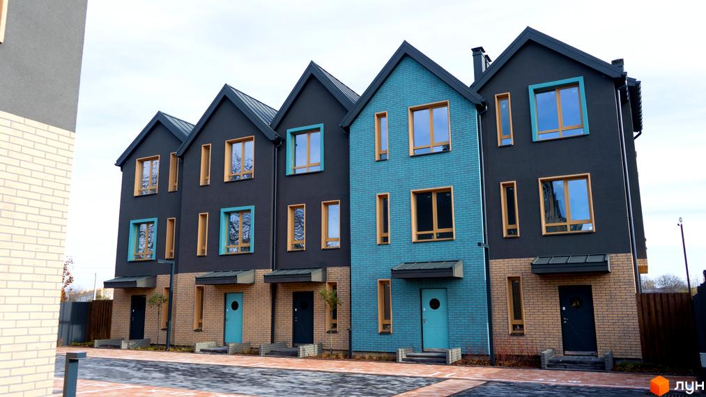 Таунхауси New Smart 13: фасади будинків з цегли та штукатурки, вікна з дерев'яними рамами, бірюзові та сірі кольори. Поруч розташована прибудинкова територія з доріжками.