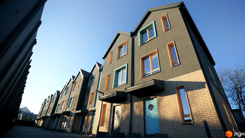 Таунхауси New Smart 13 з сірим фасадом та різнокольоровими вікнами на тлі блакитного неба. Поруч розташована доглянута прибудинкова територія.