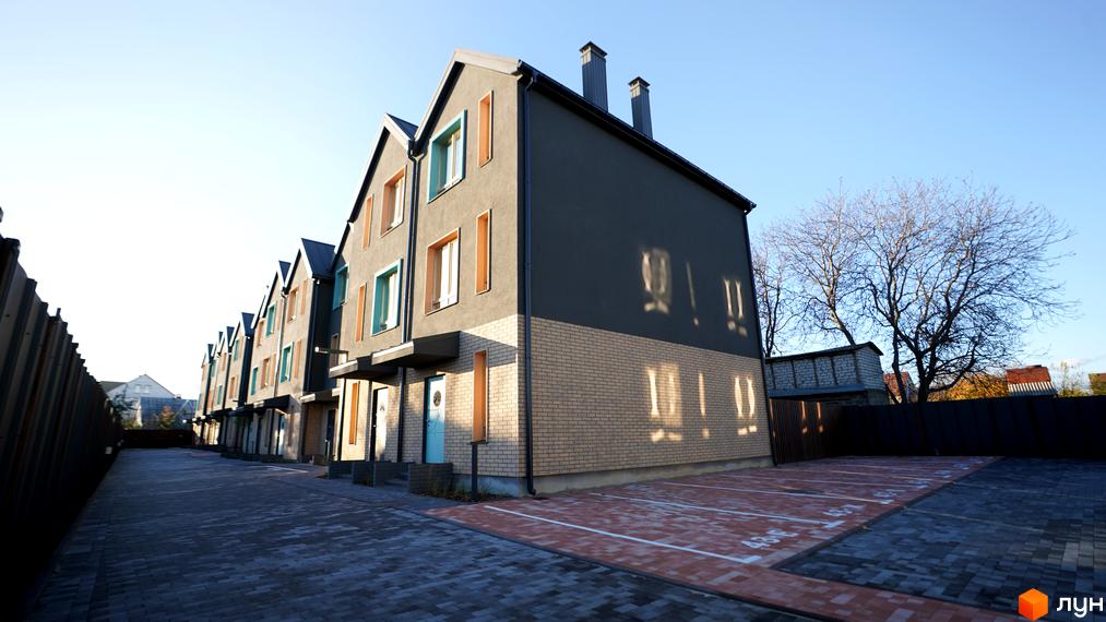 Таунхауси New Smart 13 – це сучасні будинки з цегляним цоколем та сірими фасадами, розташовані на брукованому подвір'ї з паркомісцями.