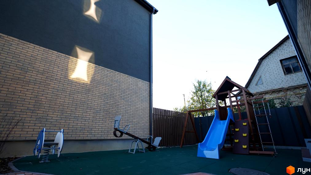 Комплекс New Smart 13. Дитячий майданчик з гіркою, гойдалкою та гойдалкою-балансиром на фоні цегляного будинку.