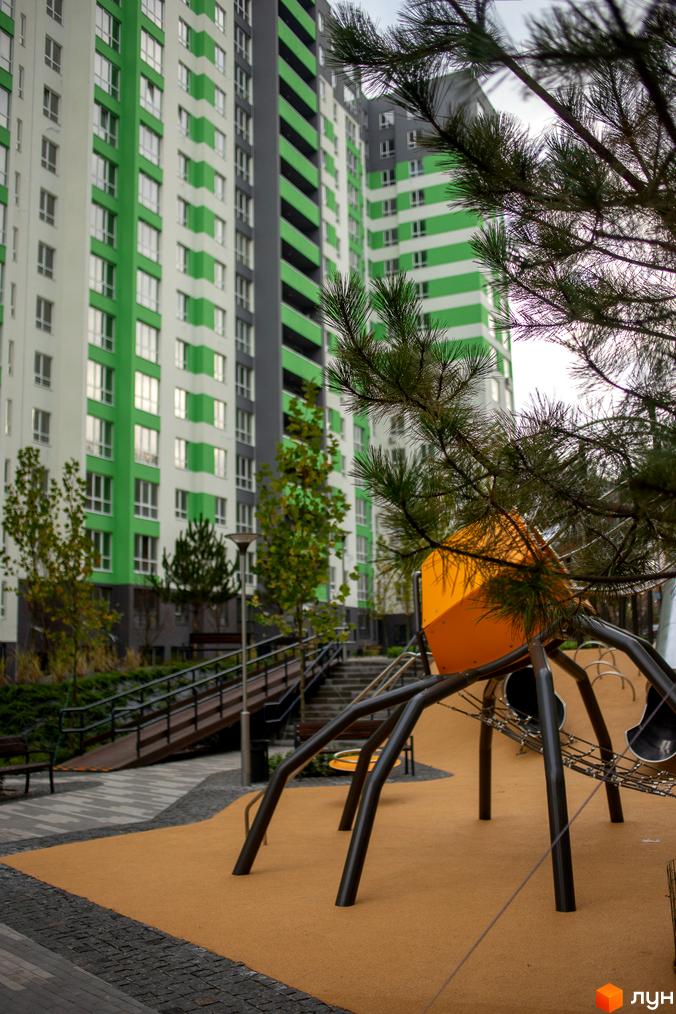 Зовнішній вигляд новобудови ЖК City Park з зеленими та білими смугами. На прибудинковій території розташований дитячий майданчик та пішохідні доріжки.