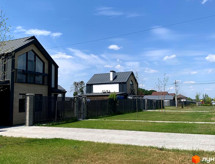 Котеджне містечко КМ Зелений Бульвар. Сучасні будинки з темними дахами та парканами, доглянута прибудинкова територія з газоном та доріжками.